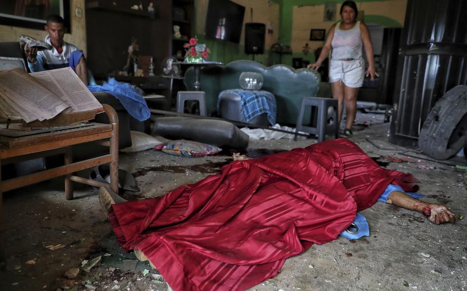 A body lays on the floor covered by a blanket.