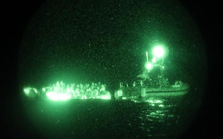 The crew of the U.S. Coast Guard cutter Glen Harris assesses an overloaded raft in the Atlantic Ocean on Jan. 5, 2022.