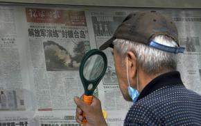 A man uses a magnifying glass to read a newspaper headline reporting on Chinese People's Liberation Army (PLA) conducting military exercises, at a stand in Beijing, Sunday, Aug. 7, 2022. U.S. Secretary of State Antony Blinken said Saturday that China should not hold hostage talks on important global matters such as the climate crisis, after Beijing cut off contacts with Washington in retaliation for U.S. House Speaker Nancy Pelosi's visit to Taiwan earlier this week. (AP Photo/Andy Wong)