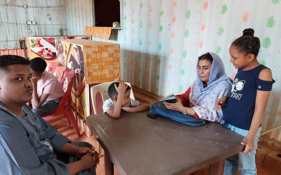 Members of the Alhajaa family sit in a cafeteria at the U.S. Embassy in Khartoum, Sudan, with their passports as they await interviews on March 9, 2023.