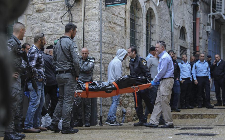 Israeli security personnel and members of Zaka Rescue and Recovery team carry the body of a Palestinian man who was fatally shot by Israeli police after he killed one Israeli and wounded four others in a shooting attack in Jerusalem’s Old City, Sunday, Nov. 21, 2021.