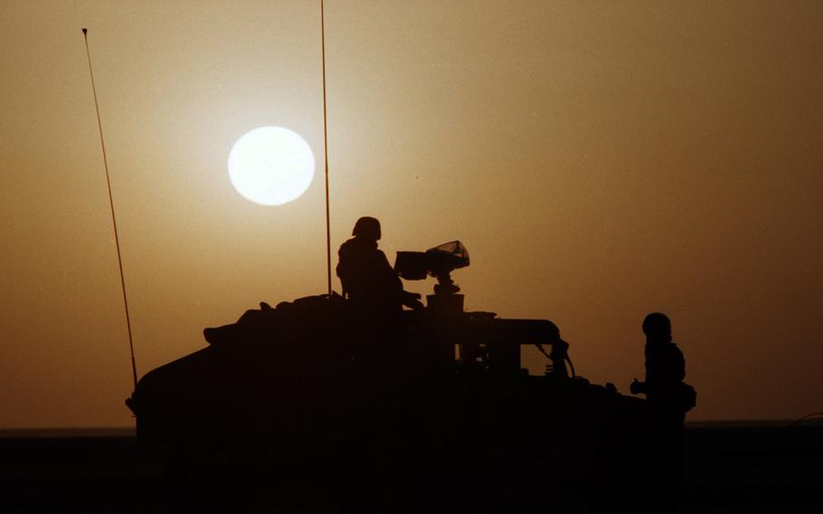 U.S. service members are silhouetted against the desert sun during the Gulf War. 