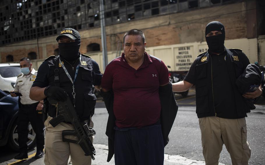 Detainee Juan Gutierrez Castro is escorted in handcuffs to court after a police operation against alleged migrant smugglers in Guatemala City, Tuesday, Aug. 2, 2022.