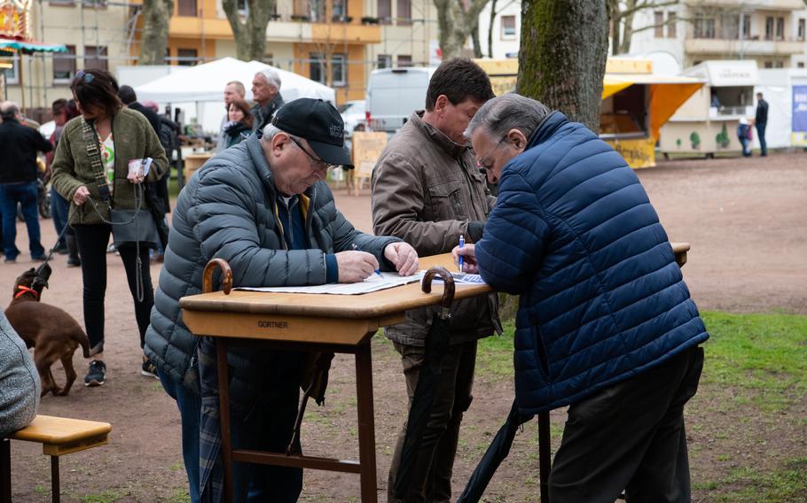 Men look at the race schedule before placing bets at Zweibrueckens grass racetrack, April 16, 2023.