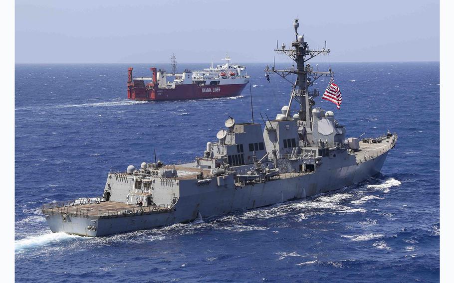 The Arleigh Burke-class guided-missile destroyer USS Truxtun (DDG 103), left, operates in the Red Sea, May 1, 2023, as another civilian ship transits in the background. 