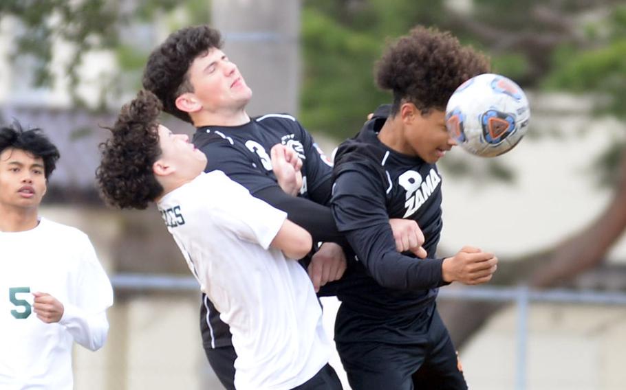 Robert D. Edgren’s Axel Nogueras and Zama‘s Connor Lape and Jaydn Parker go up to head the ball during Saturday’s DODEA-Japan boys soccer match. The Trojans won 4-0.