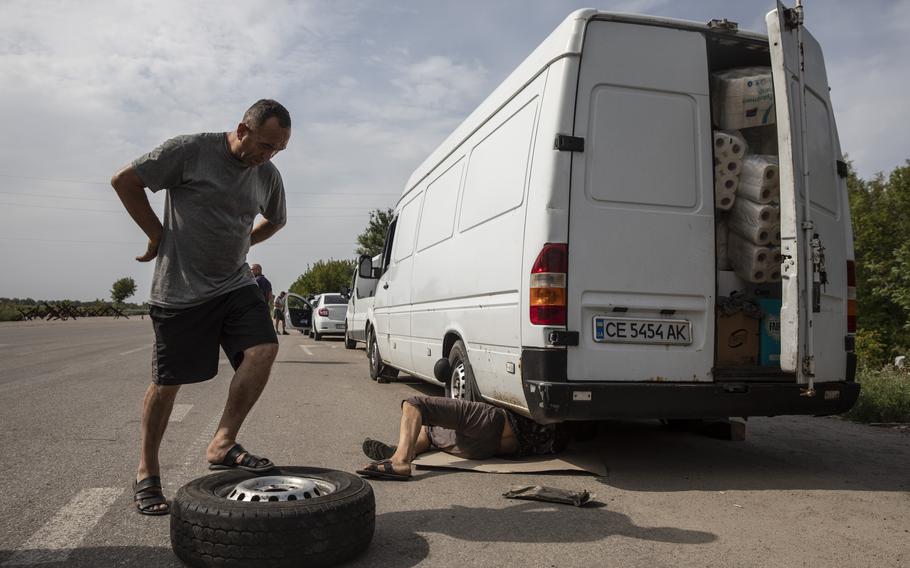 Rafik Sultanov, 53 , waits for a flat tired to be repaired on his van full of supplies on the outskirts of the village of Kamiyanske, Ukraine, on Aug. 27, 2022. 