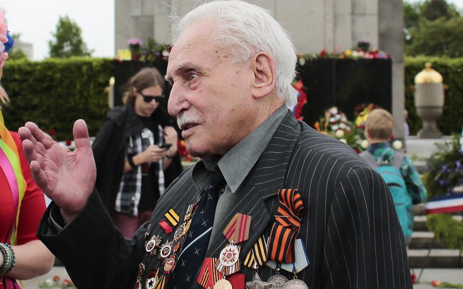 Soviet war veteran David Dushman, 92, center, speaks to people holding Ukrainian flags as he attends a wreath laying ceremony at the Russian War Memorial in the Tiergarten district of Berlin, Germany, on May 8, 2015. Dushman, the last surviving Allied soldier involved in the liberation of Auschwitz, has died.