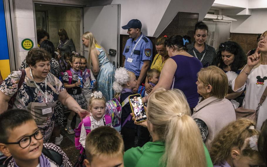 Excited mothers hug and snap cellphone photos of their children as they wait after the first session of the first day of school for first graders in the new classrooms in the underground metro station in Kharkiv, Ukraine.