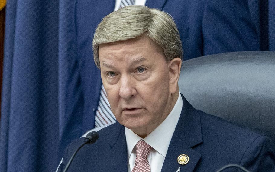 Rogers seated at a hearing with a microphone in front of him.