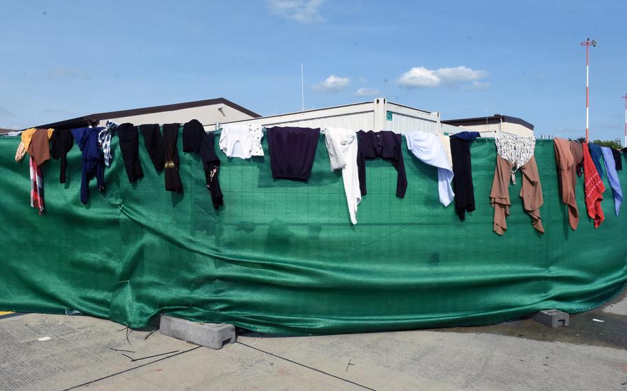 Clothing is draped over a barrier to dry in the sun inside a temporary living facility set up for evacuees from Afghanistan at Ramstein Air Base, Germany, Aug. 21, 2021.
