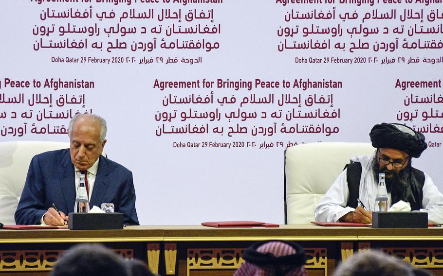 Zalmay Khalilzad, the American special envoy for Afghan reconciliation, signs a peace deal alongside the Taliban’s Mullah Abdul Ghani Baradar in Doha, Qatar, on Feb. 29, 2020. 