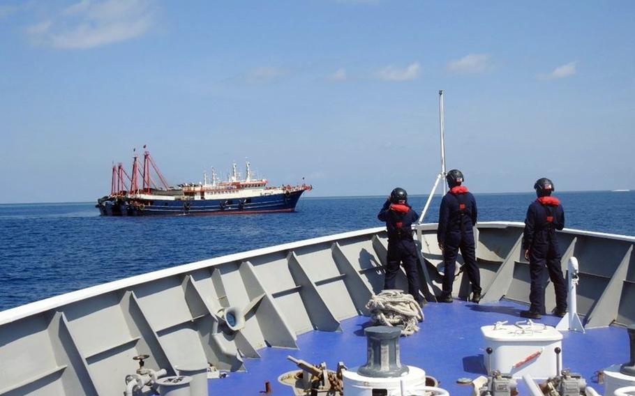 Philippine coast guardsmen survey several ships believed to be Chinese militia vessels at Sabina Shoal in the South China Sea in April 2021.