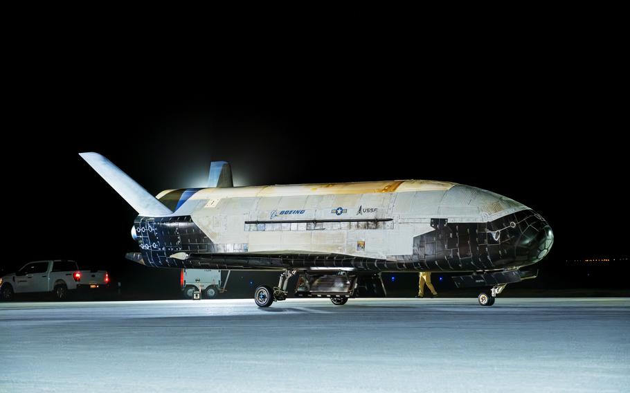 A spacecraft resembling a shuttle on a runway at night.