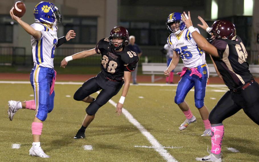 Yokota quarterback Dylan Tomas tries to unload the ball in front of onrushing Matthew C. Perry defenders Kirby Kendrick, center and Maddix LaRue.