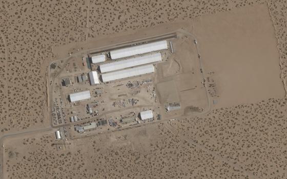 An aerial/satellite photo of white and gray buildings in a desert.