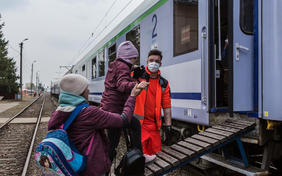 Ukrainians board a medical train with the help of a Polish medic at a train station in Medyka, Poland, on March 30, 2022.