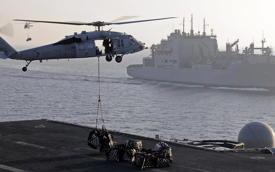 A Navy MH-60S Knighthawk helicopter assigned to Helicopter Sea Combat Squadron 12 ferries cargo from the dry cargo ship USNS Charles Drew, background, to the aircraft carrier USS Abraham Lincoln during a vertical replenishment March 1, 2012, in the Arabian Sea.