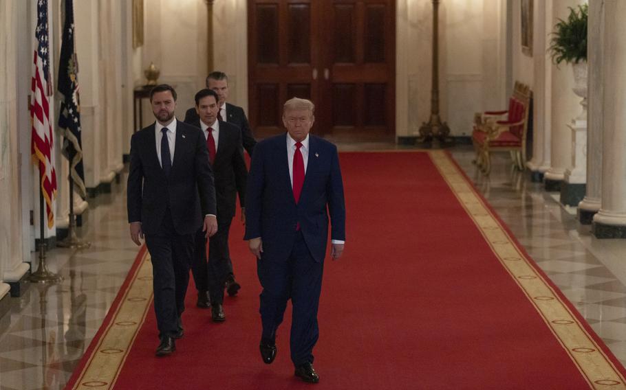 Trump, Vance, Rubio and Hegseth walk along a red-carpeted hallway in the White House.