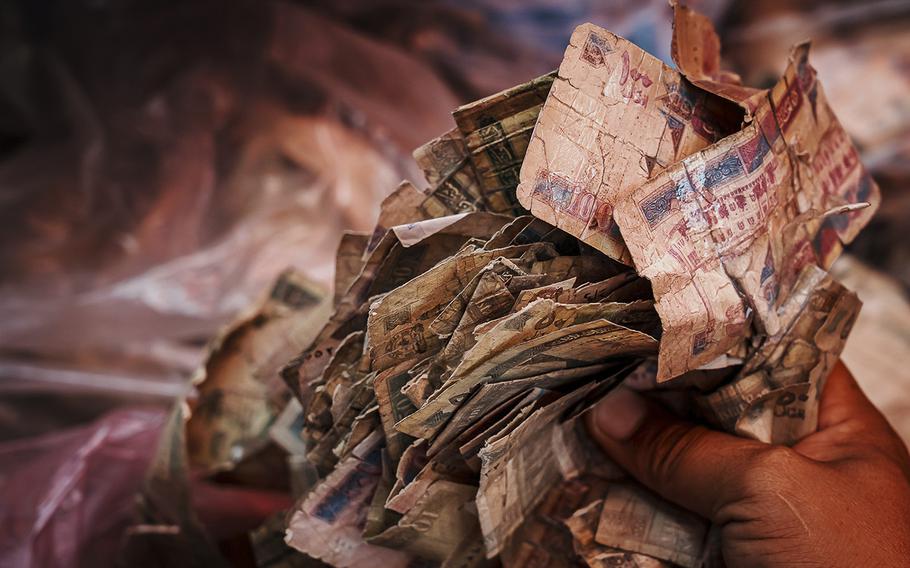 A currency converter displays a pile of extremely worn out Afghan currency at the Sarai Shahzadah, Kabul’s currency exchange market, in Kabul, Afghanistan, on Sept. 7, 2022. 