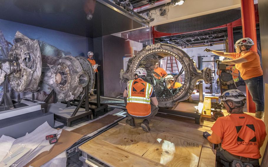 Contractors install a section of a recovered Apollo 11 F-1 engine in the “Destination Moon” gallery.