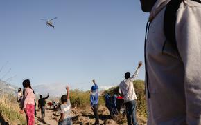 Migrants wave to a Texas Department of Public Safety helicopter after crossing the US-Mexico border through the Rio Grande in El Paso, Texas on Tuesday, April 2, 2024. MUST CREDIT: Justin Hamel/Bloomberg