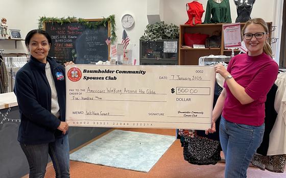 Two women standing on either side and holding up giant check