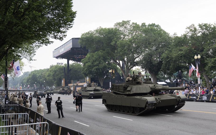 Abrams tanks roll down Pennsylvania Avenue in front of an audience.