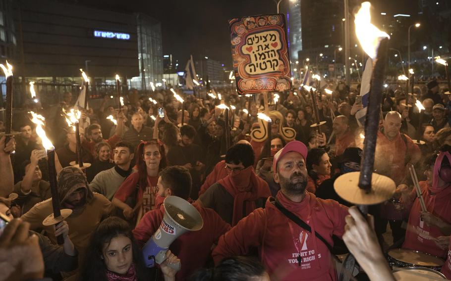 Israelis carry torches at a protest against Israeli Prime Minister Benjamin Netanyahu and his his far-right government that his opponents say threaten democracy and freedoms, in Tel Aviv, Israel, Saturday, Jan. 21, 2023. 