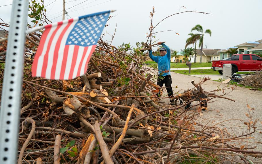 Juan Gomez, 48, of Guatemala carries branches from a storm damaged tree. He has been in the United States since 2019. 