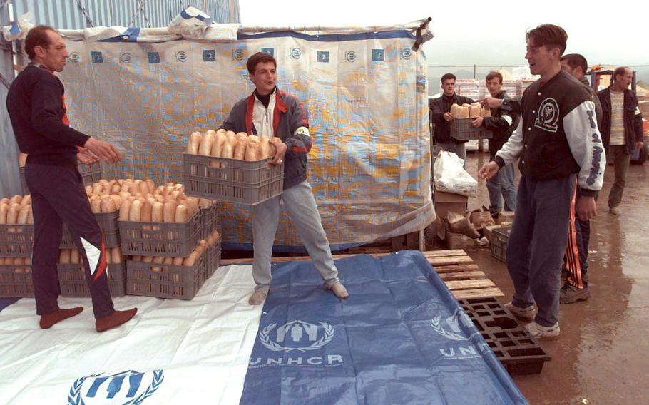 Volunteers move crates of bread to drier storage at the Brazda refugee camp in Skopje, Macedonia, April 23, 1999. The workers were Kosovo refugees volunteering their time to the Catholic Relief Service.