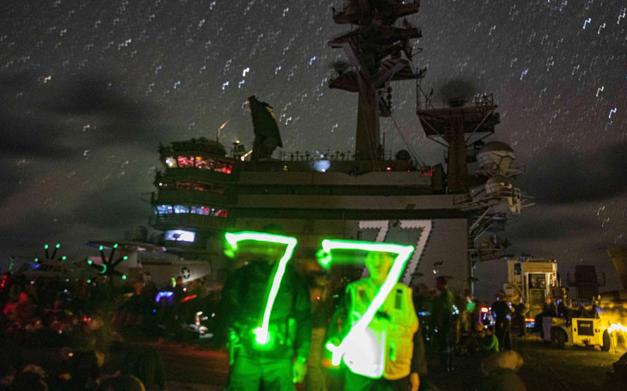 Sailors aboard the aircraft carrier USS George H.W. Bush paint the ship's hull number with their flashlights during a stargazing event on the flight deck, Aug. 19, 2022. The George H.W. Bush Carrier Strike Group passed the Strait of Gibraltar and entered the Mediterranean Sea as part of a deployment in the U.S. Naval Forces Europe-Africa area of operations, Aug. 25.