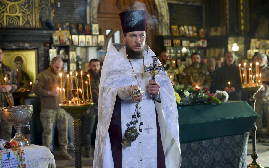 Tendrils of fragrant incense waft through the air as Father Bohdan Vayda, a priest at St. Volodymyr’s Cathedral in Kyiv, Ukraine, swings a censer to bless the soldiers and civilians gathered at a funeral Nov. 1, 2022. 