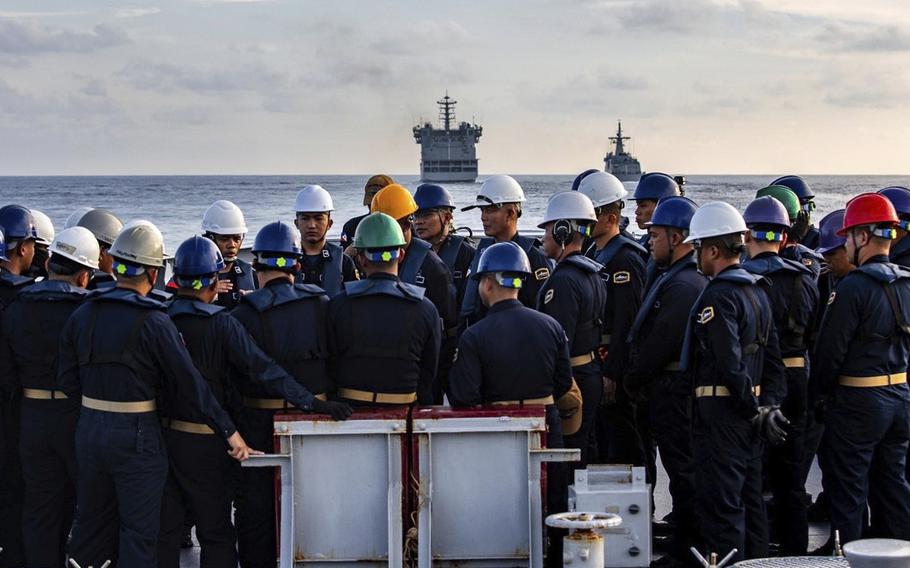 Sailors stand on a ship and listen to planning.