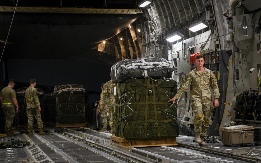 Army Staff Sgt. Jacob Engstrom of the 165th Quartermaster Company walks a bundle of humanitarian aid onto a U.S. Air Force C-17 Globemaster III on the flightline at Al Udeid Air Base, Qatar, on March 16, 2024. 