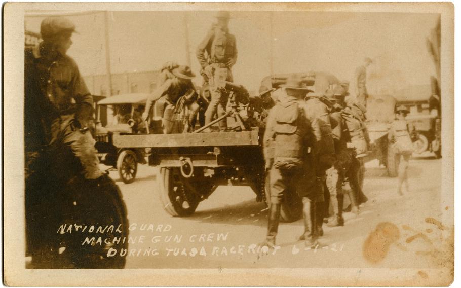 This black-and-white photographic postcard titled "National Guard Machine Gun Crew" shows a group of soldiers marching through Tulsa on June 1, 1921. 