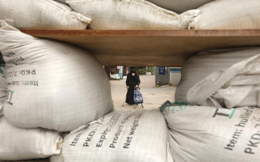 An elderly woman walks by sand bags set up for protection in Odesa, on April 12, 2022. Many of those left behind in the war are elderly people. 