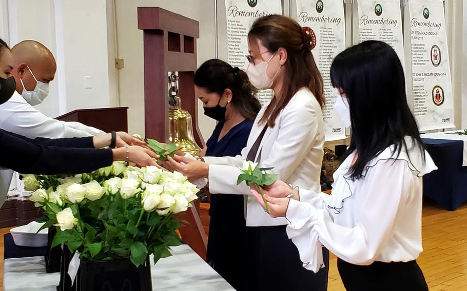 Gold Star family members Kaori Thomas, Riho Finldley and Makiko Walker accept flowers to place in memory of their husbands at Yokosuka Naval Base, Japan, Thursday, Sept. 22, 2022. 