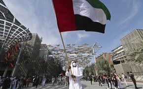FILE - A man waves the national flag during celebrations for the UAE 50th National Day, at the EXPO 2020 Dubai, in Dubai, United Arab Emirates, Dec. 2, 2021. The multibillion-dollar world’s fair in Dubai warned Tuesday, Dec. 28, 2021, that some venues on site may shut down temporarily as coronavirus cases rapidly rise after the arrival of the omicron variant. (AP Photo/Kamran Jebreili, File)
