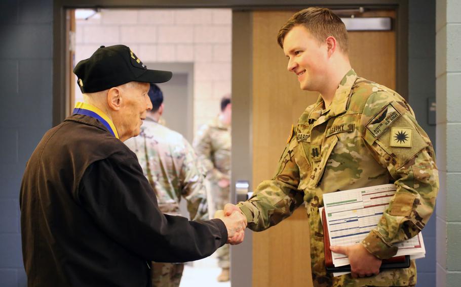 Capt. Austin Bogard, commander of Bravo Company, 1st Battalion, 168th General Support Aviation shakes hands with Capt. Dick Nelms, retired World War II pilot, during a presentation of the Knight of the Honorable Order of Saint Michael award at the Washington Army National Guard Aviation Readiness Center, Joint Base Lewis-McChord, Wash., on Sunday, March 3, 2024. The award is designed to recognize an individual’s long-term support and/or a legacy with significant and long-lasting impact to Army Aviation. While there is no specific time period for this award, it is not normally represented by a single assignment unless recognizing an enduring achievement in direct support of Army Aviation soldiers and their families.