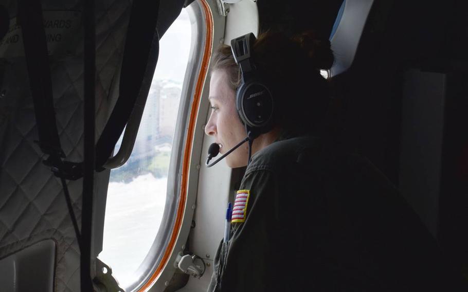 A Coast Guard flight crew member looks out the window as she’s positioned to watch for any danger on a flight to Southwest Florida on Sunday, Oct. 2, 2022. 