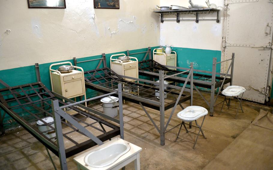 An room with metal bunk beds, bed pans and storage cabinets.