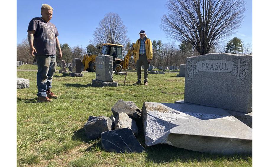Roy Chapman, a maintenance worker at St. Mary Cemetery in Northampton, Mass., looks over damaged gravestones. A driver crashed into the cemetery and damaged nearly 20 gravestones on April 8, 2023. At right is Jim McCool Jr., a retired Florence resident who volunteers his time helping Chapman. 