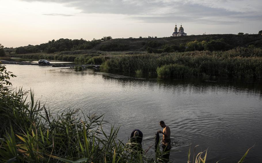 Men look for mussels as a car leaves the Kherson region on Aug. 31. 