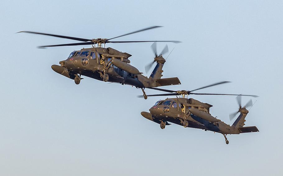 A pair of U.S. Army UH-60 Black Hawk helicopters hover above a base in Warsaw, Poland, on Feb. 14, 2022.