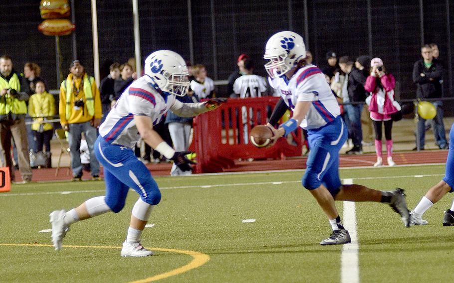 Ramstein quarterback Lucas Hollenbeck hands off to John Thompson during a DODEA-Europe Division I semifinal Friday evening in Stuttgart, Germany.