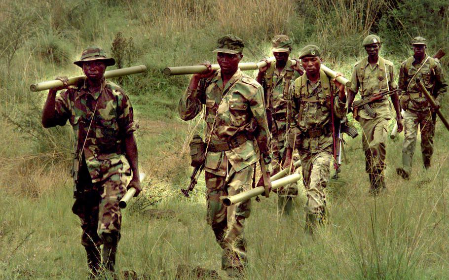 Ugandan army engineers carry explosives to clear a path through a mine field while undergoing U.S.-led peacekeeper training. 