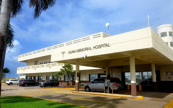 Cars are parked outside the front entrance of Guam Memorial Hospital in Tamuning, Guam, on a sunny day.