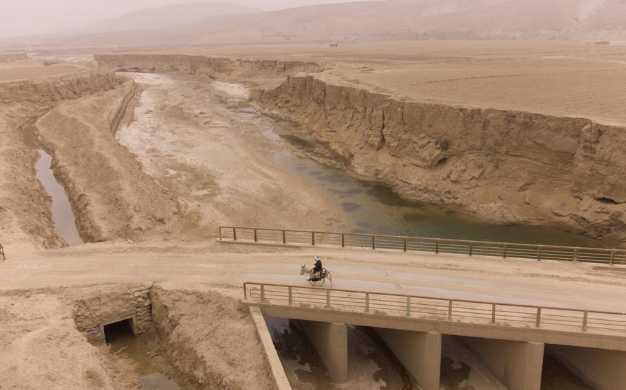 FILE - Afghan farmer uses donkey to carry water canisters across the dried-out river near Sang-e-Atash, Afghanistan, on Dec. 13, 2021. Cybersecurity and space are emerging risks to the global economy, adding to existing challenges posed by climate change and the coronavirus pandemic, the World Economic Forum said in a report Tuesday, Jan. 11, 2022. (AP Photo/Mstyslav Chernov)