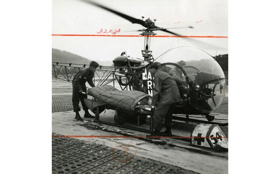 44th MASH, South Korea, Feb. 1960: SP5 Edward Coggs and S/Sgt. Walter Hettinger, both of the 54th Medical Detachment (Helicopter Ambulance) unload a patient from a H-13 Sioux helicopter for hospitalization at the 44th Mobile Army Surgical Hospital (MASH).

Pictured here is a scan of the original 1960 print created by Stars and Stripes Pacific's photo department to run in the print newspaper. The red marks indicate the crop lines. Only the middle part of the image would appear in the newspaper. As all pre-1964 Stars and Stripes Pacific negatives and slides were unwittingly destroyed by poor temporary storage in 1963, the prints developed from the late 1940s through the earlu 1960s are the only images left of Stripes' news photography from those decades. Stars and Stripes' archives team is scanning these prints to ensure their preservation. 

Looking for Stars and Stripes’ historic coverage? Subscribe to Stars and Stripes’ historic newspaper archive! We have digitized our 1948-1999 European and Pacific editions, as well as several of our WWII editions and made them available online through https://starsandstripes.newspaperarchive.com/

METADATA: Pacific; South Korea; military medical; hospital; health care; DMZ; U.S. Army; medvac; medical evacuation; newspaper history;